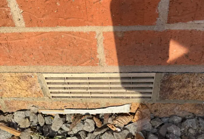 Snagging survey - A brick wall showing an airbrick incorrectly placed and bridging the damp course