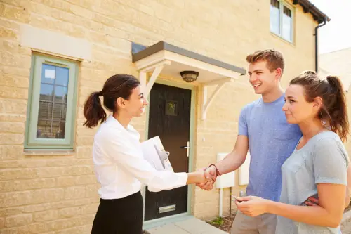 Estate agent completing sale with smiling young couple,