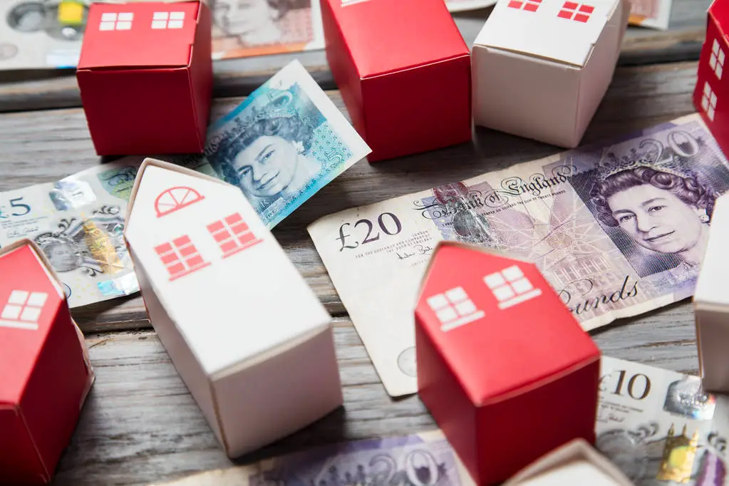 Money and small models of houses on a wooden table, showcasing EPCs and mortgage eligibility.